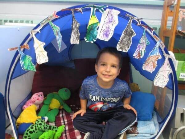 Young boy in pop-up tent hung with bat drawings